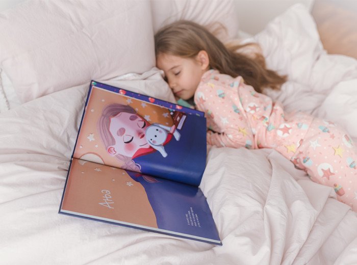 Devojčica spava sa otvorenom knjigom pored sebe